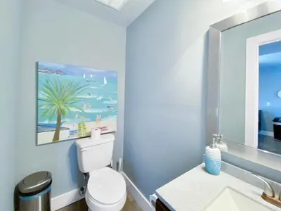 a bathroom with a white toilet and a painting of a beach at Shoreline Townhomes 10 l Steps to the Beach l Beautiful views from 2nd and 3rd balconies in Inlet Beach