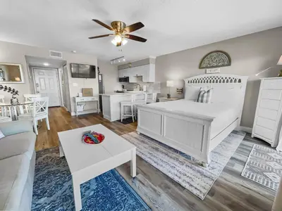 a bedroom with a white bed and a living room at SummerSalt l Ocean Views l Heated Community Pool l Dog Friendly in Seagrove Beach