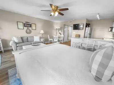 a living room with a white bed and a kitchen at SummerSalt l Ocean Views l Heated Community Pool l Dog Friendly in Seagrove Beach