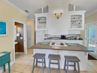 a kitchen with white cabinets and a island with stools at SummerTowne 1 At Pier Park l Amazing Ocean Views l Dog Friendly l Community Pool in Panama City Beach