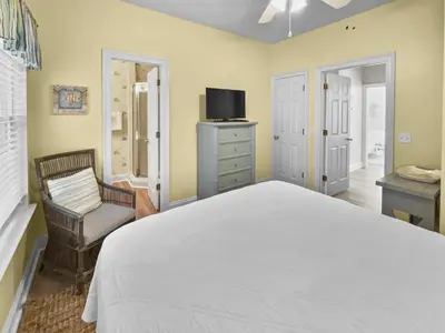 a bedroom with a bed and a tv and a chair at SummerTowne 1 At Pier Park l Amazing Ocean Views l Dog Friendly l Community Pool in Panama City Beach