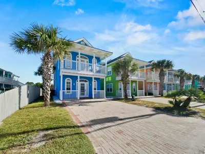 a large blue house with palm trees in front of it at SummerTowne 1 At Pier Park l Amazing Ocean Views l Dog Friendly l Community Pool in Panama City Beach
