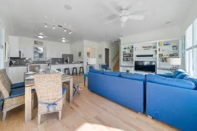 a living room with blue couches and a kitchen at Surfer Dog l Beachfront Pool l Includes Beach Chairs and Bikes in Inlet Beach