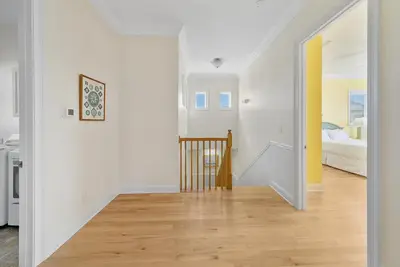 a hallway with white walls and a staircase with a bed at Surfer Dog l Beachfront Pool l Includes Beach Chairs and Bikes in Inlet Beach