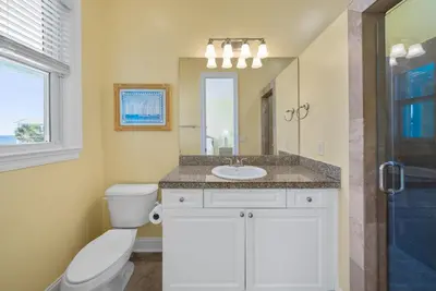a bathroom with a toilet and a sink and a mirror at Surfer Dog l Beachfront Pool l Includes Beach Chairs and Bikes in Inlet Beach