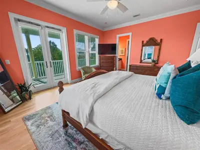 a bedroom with orange walls and a bed and a mirror at Surfer Dog l Beachfront Pool l Includes Beach Chairs and Bikes in Inlet Beach