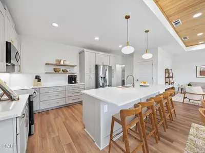 a kitchen with a large white island and wooden floors at PCB Luxe 4BR, Heated Pool, 3 Blks to Beach in Panama City Beach