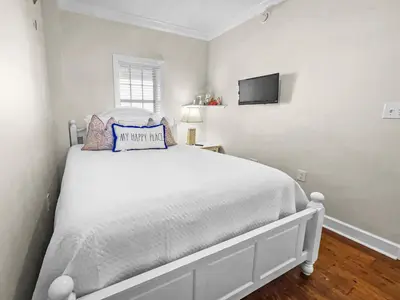 a bedroom with a white bed with a tv on the wall at The Flipside 30A l Heated Community Pool and Hot Tub l Steps to Rosemary Beach in Rosemary Beach