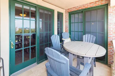 a porch with a table and chairs on a balcony at The Flipside 30A l Heated Community Pool and Hot Tub l Steps to Rosemary Beach in Rosemary Beach