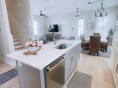 a white kitchen with a sink and a living room at The Way of Water l Community Pool l 2 Bikes included in Inlet Beach