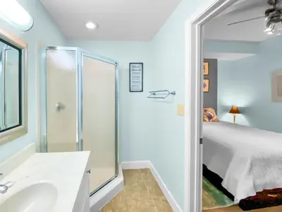 a bathroom with a shower and a sink and a bed at Tidewater 311 l Beachfront with pristine views l Heated Pool & Jacuzzi l Gym and Game room and Theatre in Panama City Beach