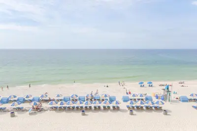 a group of chairs and umbrellas on a beach at Tidewater 311 l Beachfront with pristine views l Heated Pool & Jacuzzi l Gym and Game room and Theatre in Panama City Beach