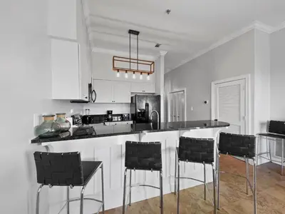 a kitchen with a bar with black chairs in it at Twickenham l Heated Community Pool l Private Balcony l Close to Rosemary in Rosemary Beach