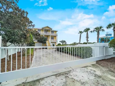 a white fence in front of a house with palm trees at Turtle Watch l Beachfront Pool l Includes Bikes and Beach Chair in Inlet Beach