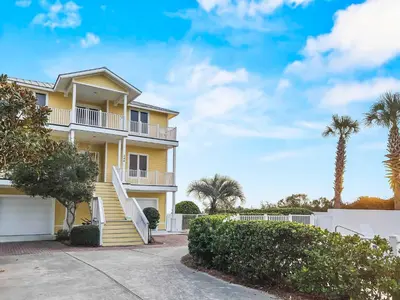 a yellow house with a white fence and palm trees at Turtle Watch l Beachfront Pool l Includes Bikes and Beach Chair in Inlet Beach