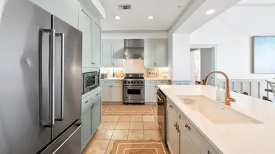 a kitchen with white cabinets and a stainless steel refrigerator at Vitamin Sea l Beachfront l 4 Bikes Included in Inlet Beach