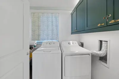 a kitchen with a washer and dryer and green cabinets at Vitamin Sea l Beachfront l 4 Bikes Included in Inlet Beach
