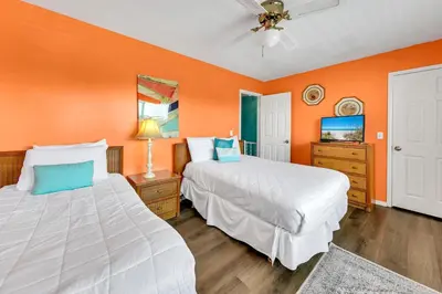 two beds in a room with orange walls at Laguna Beach Breeze in Panama City Beach