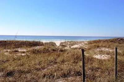 a beach with a fence and the ocean in the background at Laguna Beach Breeze in Panama City Beach