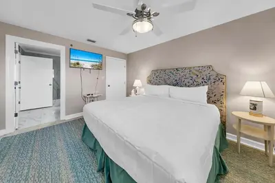 a bedroom with a large white bed and a bathroom at Sterling Reef 301 by Emerald Coast Retreats in Panama City Beach