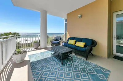a patio with a couch and a table on a balcony at Sterling Reef 301 by Emerald Coast Retreats in Panama City Beach