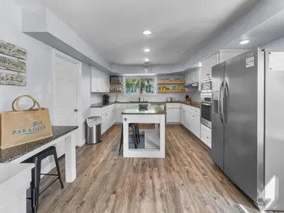 a kitchen with white cabinets and a stainless steel refrigerator at Lagerheads l Beach Views l Private Pool l Dog Friendly l Includes 4 Bikes in Inlet Beach