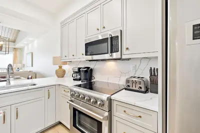 a kitchen with white cabinets and a stove and microwave at HP 42W Peaceful Nest by 30A Escapes in Rosemary Beach