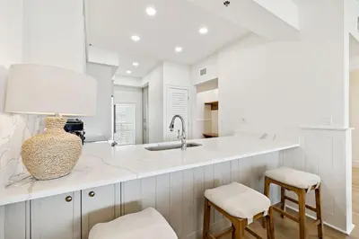 a kitchen with white counters and a sink and stools at HP 42W Peaceful Nest by 30A Escapes in Rosemary Beach