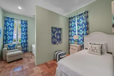 a bedroom with a bed and a chair and windows at Luxury Rosemary 4BR Villa with Private Pool in Rosemary Beach