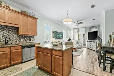 a kitchen with wooden cabinets and a living room at Paradise 2205 in Santa Rosa Beach