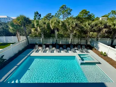 a swimming pool with chaises and chairs on a balcony at Pelican Perch in Seagrove Beach