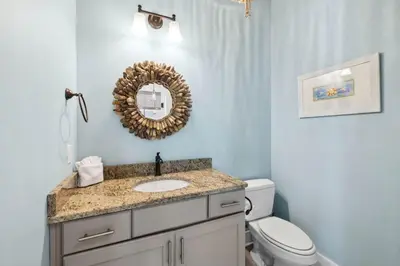 a bathroom with a sink and a toilet and a mirror at Pelican Perch in Seagrove Beach