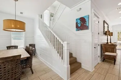 a staircase in a home with white walls and a table and chairs at Pelican Perch in Seagrove Beach