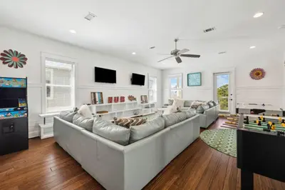 a living room with a large couch and a tv at Pelican Perch in Seagrove Beach