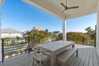 a wooden porch with a table and chairs on a deck at Anchors Aweigh in Seacrest