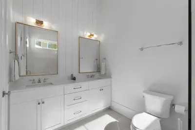 a white bathroom with a toilet and a mirror at Anchors Aweigh in Seacrest
