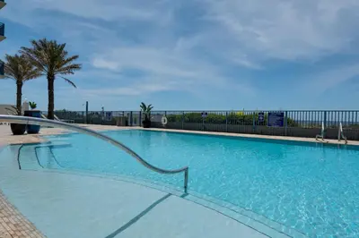 a large blue swimming pool with a fence and palm trees at Sterling Breeze 307A by Emerald Coast Retreats in Panama City Beach