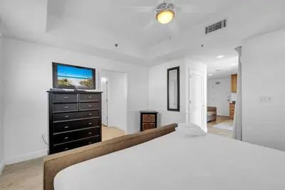 a white bedroom with a bed and a tv at Sterling Breeze 307A by Emerald Coast Retreats in Panama City Beach