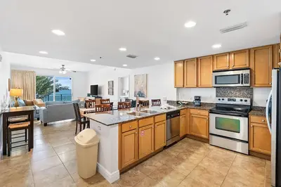 a kitchen with wooden cabinets and a living room at Sterling Breeze 307B by Emerald Coast Retreats in Panama City Beach