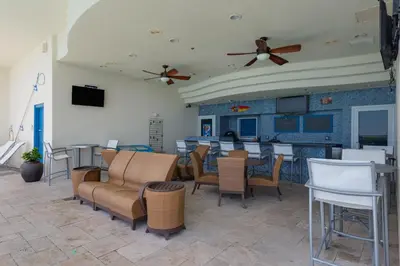 a living room with chairs and tables and a bar at Sterling Breeze 307B by Emerald Coast Retreats in Panama City Beach