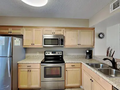 a kitchen with a stove and a microwave at Dunes of Panama #B501 in Panama City Beach