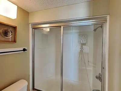 a bathroom with a glass shower with a toilet at Dunes of Panama #B501 in Panama City Beach
