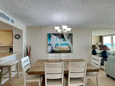 a dining room with a table and white chairs at Dunes of Panama #B501 in Panama City Beach