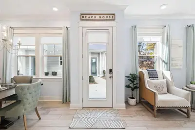 a living room with a door with a sign that reads eight house at Blue Dreams 125 W Pine Lands Loop Unit A in Inlet Beach