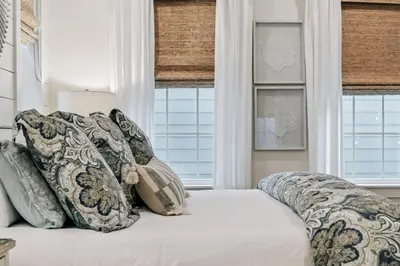 a bed with pillows on it in a room with windows at Beach Heaven in Inlet Beach