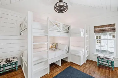 a bedroom with white bunk beds and a window at Beach Heaven in Inlet Beach