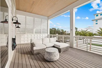 a porch with a couch and a stool on a deck at 30A Backyard Paradise - Huge Luxury Vacation Home with Gulf Views & Private Pool in Rosemary Beach