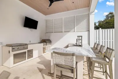 a kitchen with a table and chairs and a television at 30A Backyard Paradise - Huge Luxury Vacation Home with Gulf Views & Private Pool in Rosemary Beach