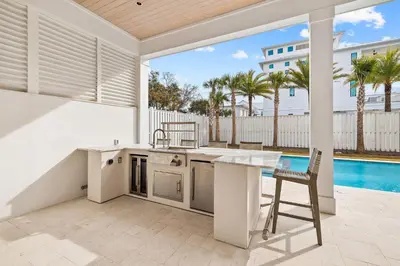 a kitchen with a table and a chair next to a pool at 30A Backyard Paradise - Huge Luxury Vacation Home with Gulf Views & Private Pool in Rosemary Beach