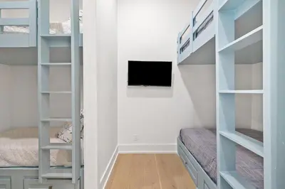 a bedroom with bunk beds and a tv at 30A Backyard Paradise - Huge Luxury Vacation Home with Gulf Views & Private Pool in Rosemary Beach